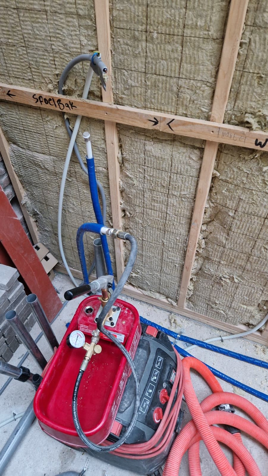 Druktest met rode pomp op leidingwerk voor een spoelbak